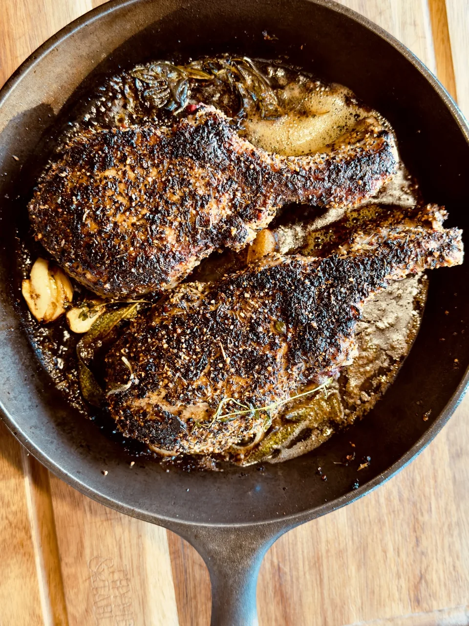 Thick bone-in pork chops butter-basting in cast iron with garlic and herbs