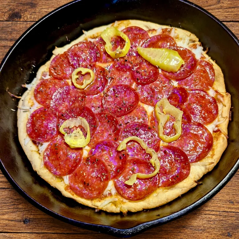 Crescent-roll pepperoni pizza with banana pepper rings baked in a black cast-iron skillet